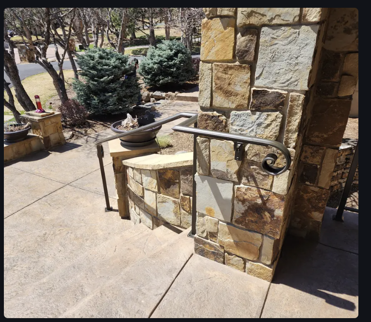 Exterior wrought iron handrail with decorative scroll on stone patio
